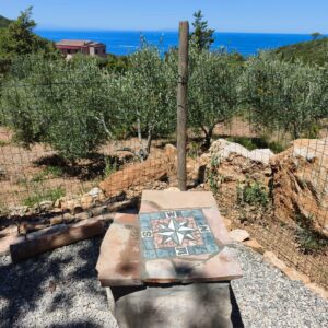 Vista sul mare dell’Isola d’Elba dal giardino del glamping con tavolo decorato a rosa dei venti